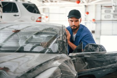 Kirli araba garajdaki oto tamircisi tarafından taşınır. Onarım servisi.