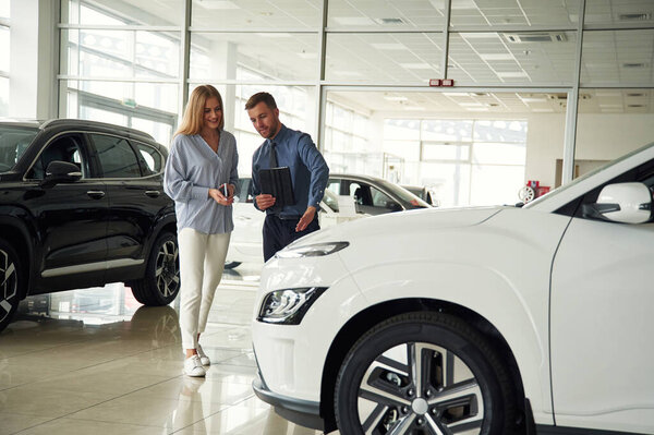 Мужчина в формальной одежде с женщиной-клиентом на электромобиле.