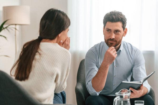 Psychologist is helping. With woman. Doctor in formal clothes is working in the cabinet.