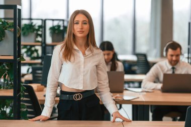 Kadın iş arkadaşlarının önünde duruyor. Resmi kıyafetli iş adamları ofiste birlikte çalışıyorlar..