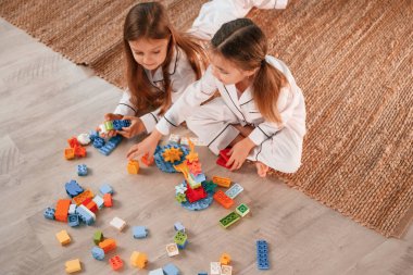 Yukarıdan bak. İnşaat oyunu oynuyorum. İki küçük kız yurt odasında birlikte eğleniyorlar..