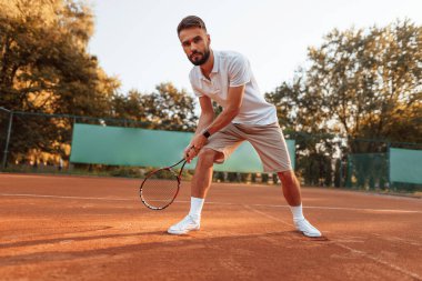 Aktif eğitim. Genç adam güneşli bir günde tenis kortunda..