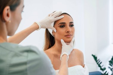 Nihai sonuçlar kontrol ediliyor. Kadın yüzü güzellik salonunda güzellik uzmanından yüz bakımı alıyor.