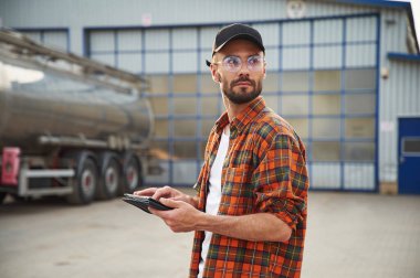 Tableti tutuyorum. Gündelik giysiler içindeki genç kamyon şoförü..