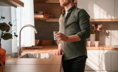 Bir bardak suyla. Yakışıklı adam gündüz vakti mutfakta olur..