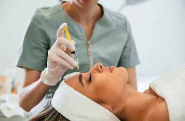 Yandan bak. Enjeksiyon yapıyorum. Kadın yüzü güzellik salonunda güzellik uzmanları tarafından tedavi ediliyor..