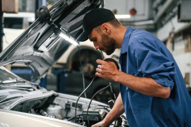 Kabloyu ayarlar. Otomobil tamircisi garajda çalışıyor. Onarım servisi.