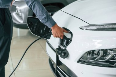 Elektrikli araba prizine şarj aleti takıyorum. Erkeğin yakın görüntüsü.