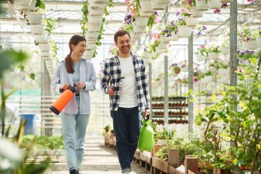 Çiçekçi adam ve kadın parlak serada birlikte çalışıyorlar..