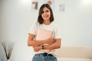 Dizüstü bilgisayarı elimde tutuyorum. Günlük giysiler içinde güzel bir kadın evde, yurt odasında..