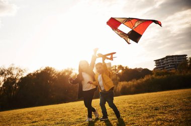 Birlikte koşmak. İki çocuk yaz sahasında uçurtmayla oynuyorlar..