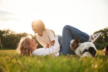 Yere yatıyordu. Güzel anne ve küçük kızı ve köpekleri yaz tarlasında beraberler..