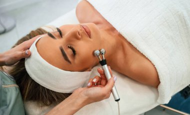 Masaj silindiri kullanılır. Kadın yüzü güzellik salonunda güzellik uzmanları tarafından tedavi ediliyor..