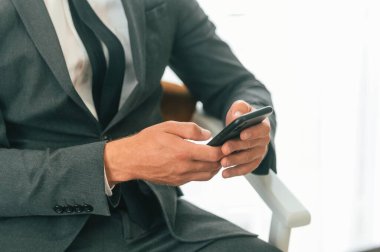 Akıllı telefon kullanan ve oturan iş adamının yakın görüntüsü.