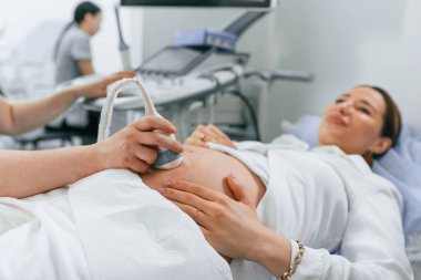 Hamile kadın hastanede yatıyor, doktor ultrason yapıyor..