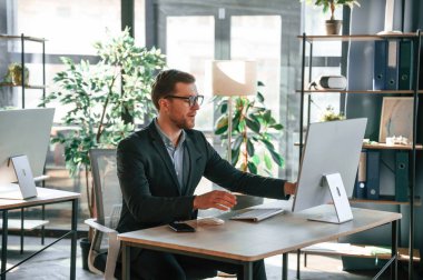 İş adamı bilgisayar başında oturuyor ve ofiste çalışıyor..