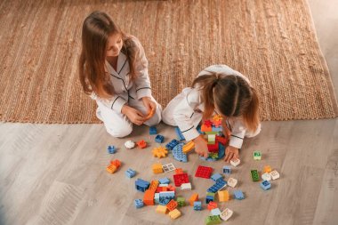 Plastik inşaat oyuncaklarının çoğu. İki küçük kız evcil odada oynuyorlar ve eğleniyorlar..