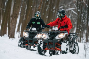 Aktif eğlence kavramı. Kış ormanında iki kişi ATV kullanıyor..