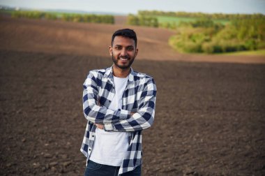 Gülümsüyor, kolları bağlı duruyor. Yakışıklı Hintli adam tarım alanında..