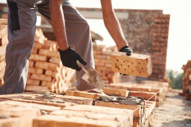 Tuğlaları yerleştiriyorum. İnşaat alanında çalışan adamın yakın görüntüsü..