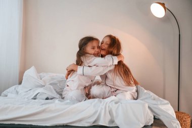 Yatakta birbirimize sarılıyoruz. İki küçük kız evcil odada oynuyorlar ve eğleniyorlar..