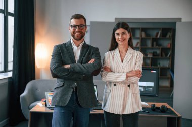 Kollarını kavuşturmuş duruyorsun. Modern ofiste iki çalışan birlikte çalışıyor..