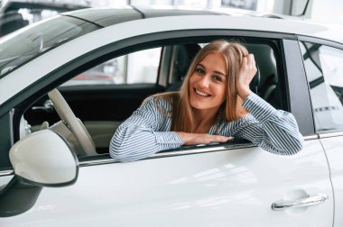 Açık pencereyle kapıya yaslanarak. Güzel kadın modern arabasıyla içeride..