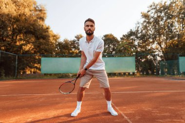 Aktif eğitim. Genç adam güneşli bir günde tenis kortunda..