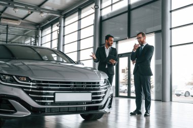 Otomobilden bahsediyoruz. Adam galeride müşteriye danışıyor..