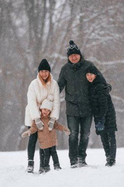 Ön manzara. Mutlu aile dışarıda, kışın birlikte kar tatilinin tadını çıkarıyorlar..