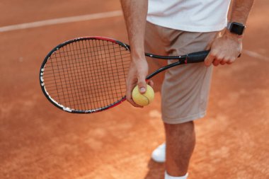Manzarayı kapat. Raketle. Genç adam güneşli bir günde tenis kortunda..