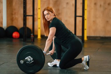 Halterle yerde oturuyor. Güzel, güçlü kadın spor salonunda..