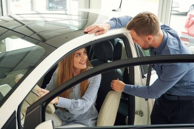 İçeriyi deniyorum. Resmi elbiseli adam elektrikli arabalı kadın müşteriyle birlikte..