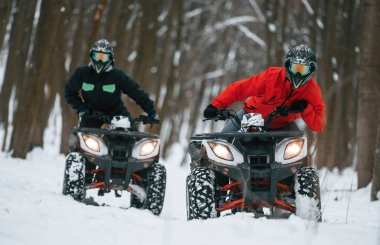 Aktif eğlence kavramı. Kış ormanında iki kişi ATV kullanıyor..