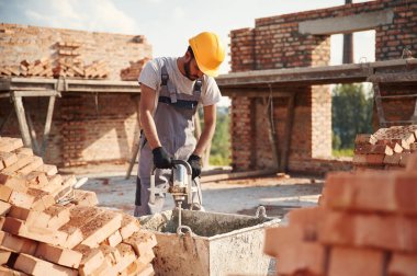 Betonu karıştırmak için bir aletle. Yakışıklı Hintli adam şantiyede..