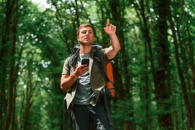 Navigasyon için akıllı telefonla yolu arıyorum. Yaz ormanında bir turist. Keşif ve eğlence kavramı.