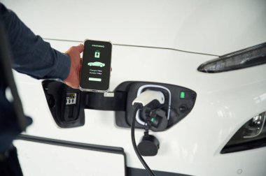 Akıllı telefon uygulaması şarj ediliyor. Elektrikli arabalı adamın yakın görüntüsü..