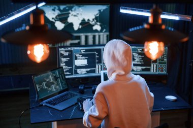 Beyaz kapüşonlu. Genç profesyonel bilgisayar korsanı bilgisayar başında ve ekranlar hakkında çok fazla bilgiye sahip..