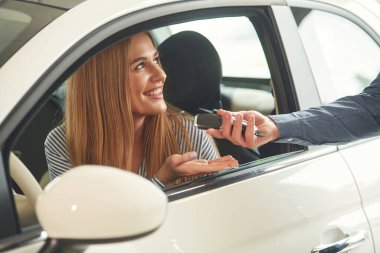 Anahtarları veriyorum. Resmi elbiseli adam elektrikli arabalı kadın müşteriyle birlikte..