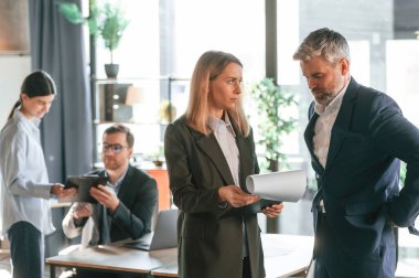 Sohbet ediyoruz, plan hakkında konuşuyoruz. Bir grup iş adamı modern ofiste çalışıyor..