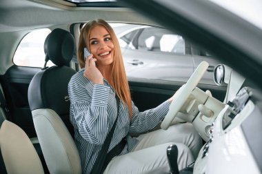 İçeride oturup telefonla konuşuyorlar. Güzel kadın modern arabasıyla içeride..