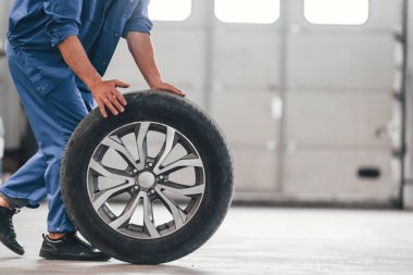 Yeni lastikle yürüyorum. Otomobil tamircisi garajda çalışıyor. Onarım servisi.