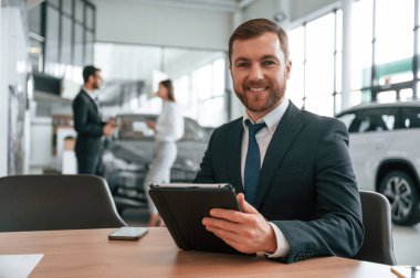 Grafik tablet kullanarak. Araba galerisinde üç kişi birlikte çalışıyor..