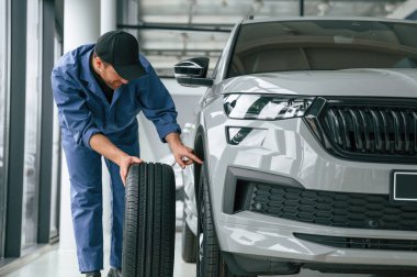 Lastiği değiştiriyorum. Mavi üniformalı adam araba servisinde çalışıyor..