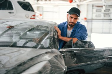 Yıkanması gereken kirli arabayı kaldırıyorum. Otomobil tamircisi garajda çalışıyor. Onarım servisi.