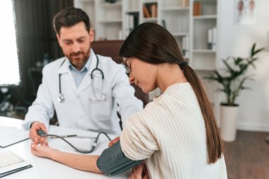 Tansiyon ölçümü. Bir kadınla. Resmi kıyafetli doktor dolapta çalışıyor..