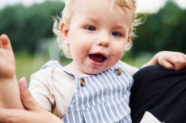Sevimli ve mutlu küçük çocuk kadın elleriyle tutuluyor..
