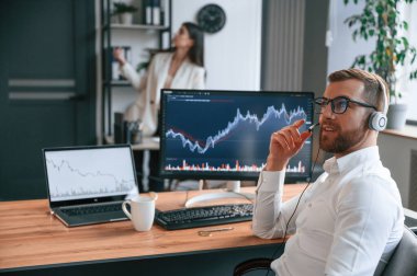 Ekranda grafikleri değiştirin. Modern ofiste iki çalışan birlikte çalışıyor..