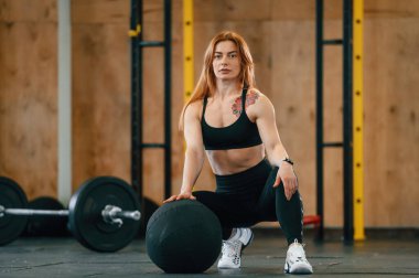 Ön manzara. Otururken, halterler yere. Güzel, güçlü kadın spor salonunda..