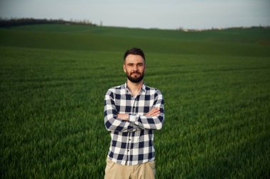 Kollarını kavuşturmuş duruyorsun. Yakışıklı genç adam tarım alanında..